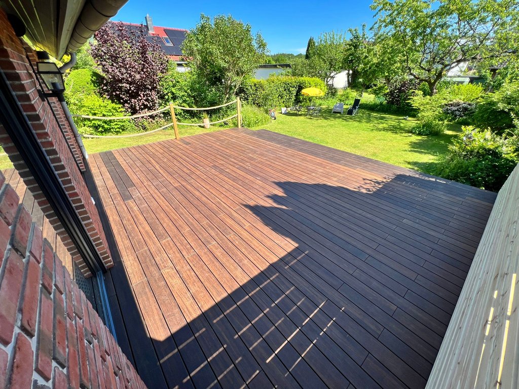 eine dunkle Holzterrasse mit Blick in den Garten